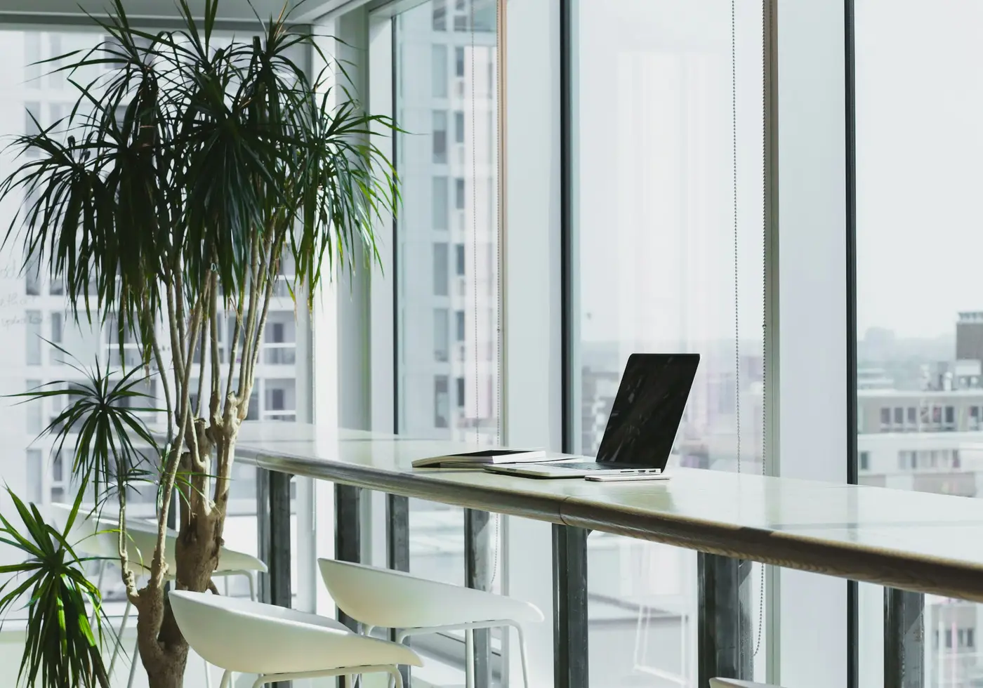 A laptop on a counter beside a window in a bright office
